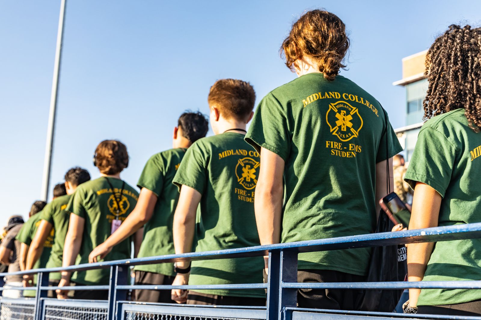 Climbers in green shirts on the stadium rail